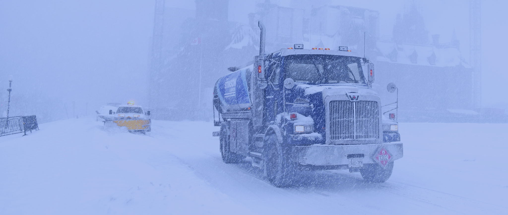 A truck utilizing custom GPS tracking solutions for trucking fleets from On Demand Tracking drives through a snowstorm in a remote location