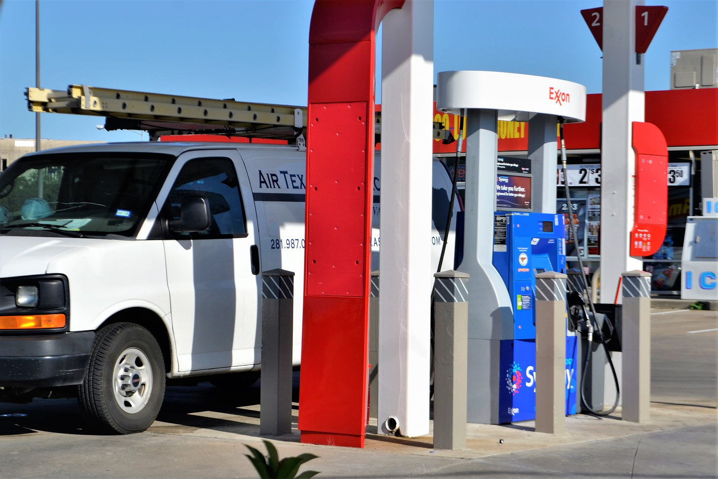 A white client fleet vehicle at a gas pump to showcase custom driver reports provided by Quartix Tracking and On Demand Tracking